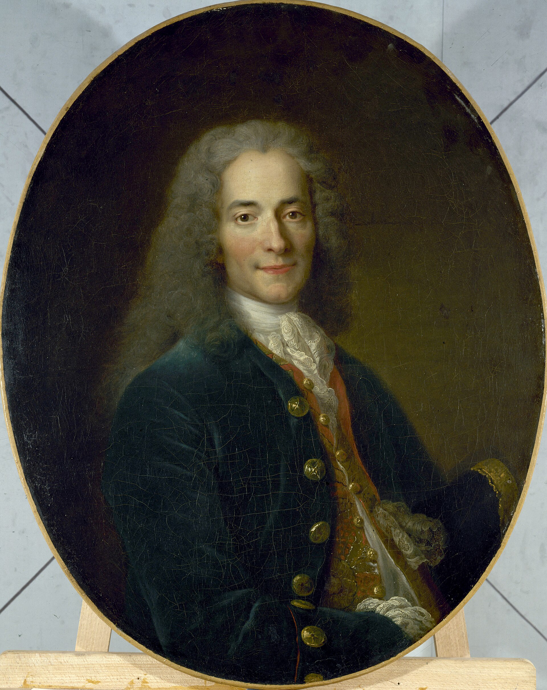 Portrait peint de Voltaire, perruque et sourire ironique.